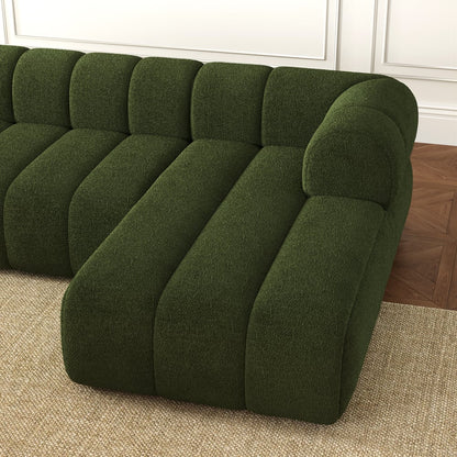Green sectional sofa in a room with wooden flooring and white walls.
