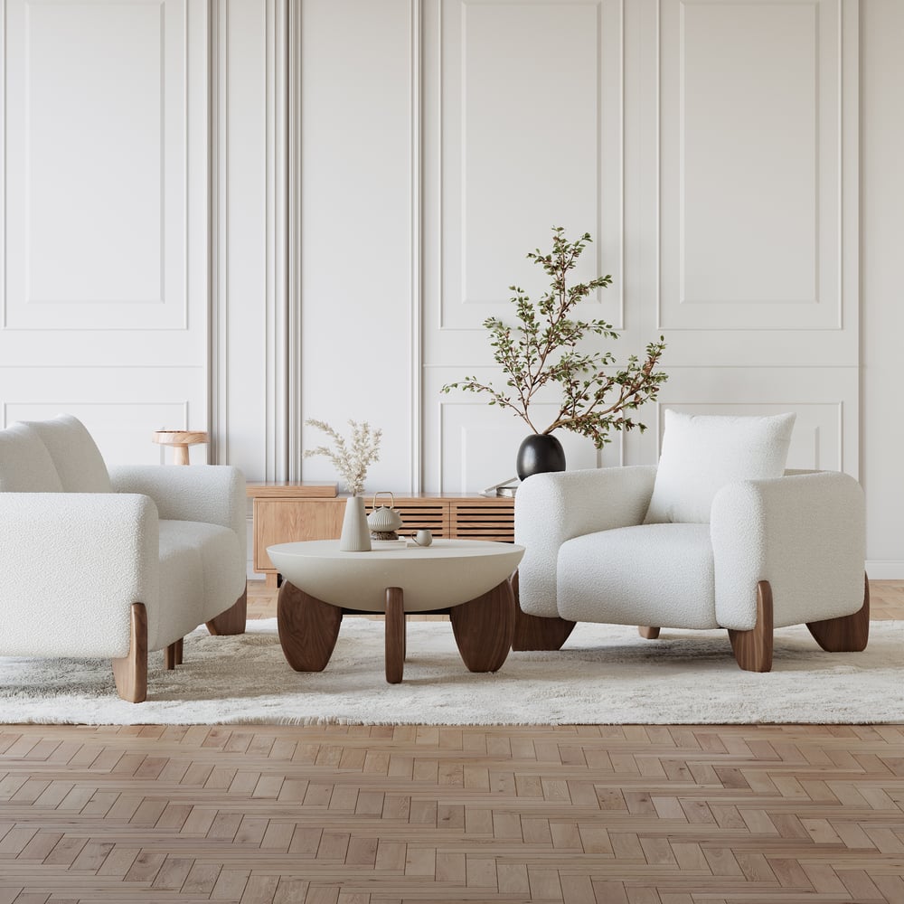 Modern living room with white armchairs, a wooden coffee table, and decorative elements.