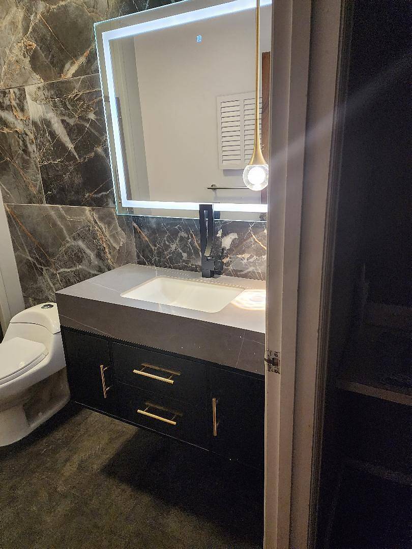 Bathroom vanity with sink and mirror in a marble-tiled bathroom.