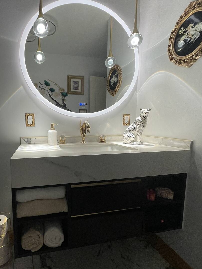 Bathroom vanity with round mirror, lights, and decorative items.