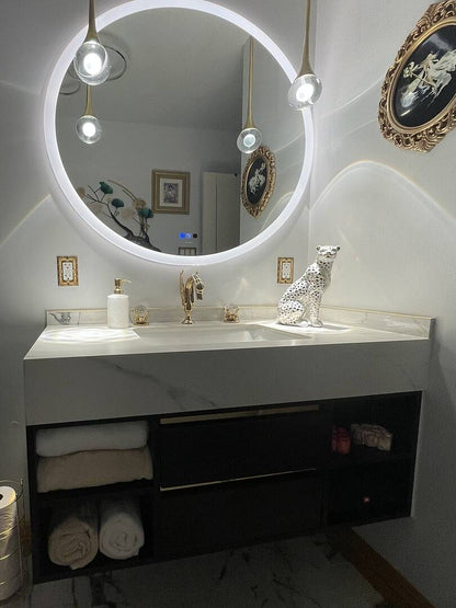 Bathroom vanity with round mirror, lights, and decorative items.