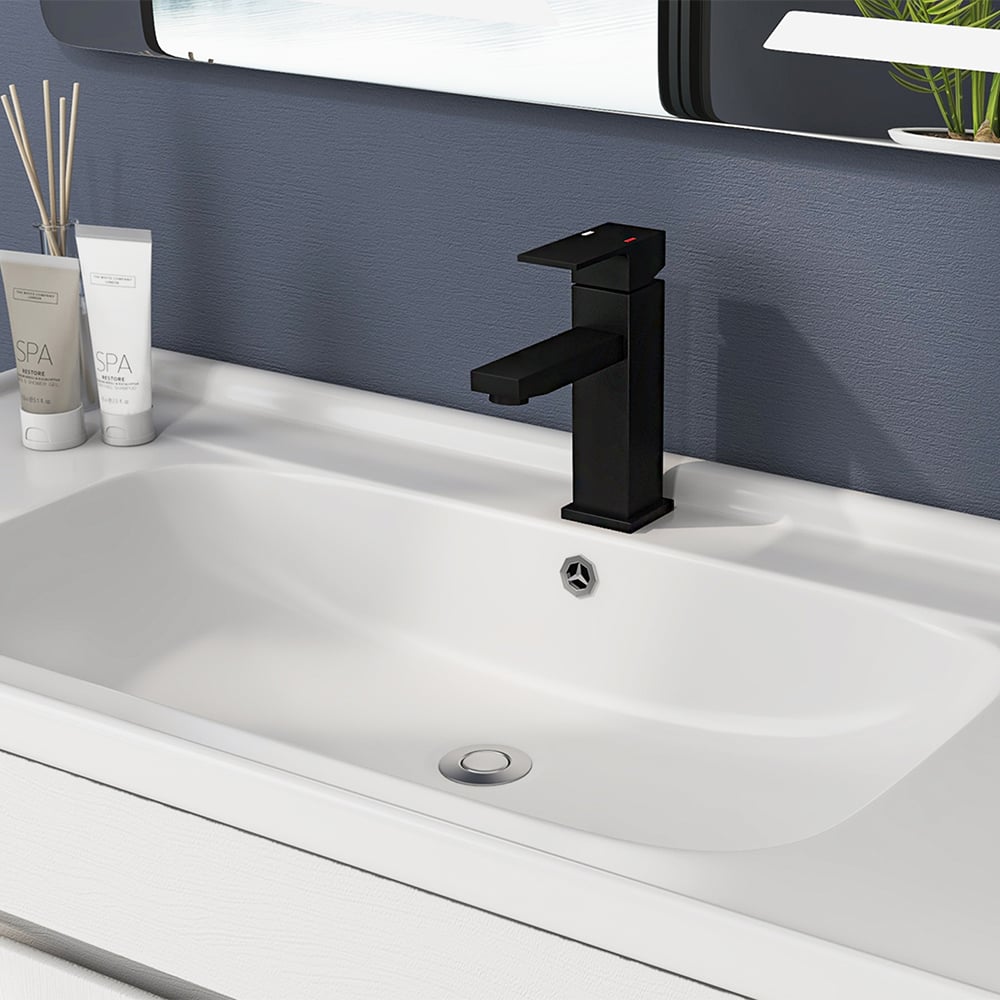 Black faucet on a white sink with a blue wall and decorative items in the background