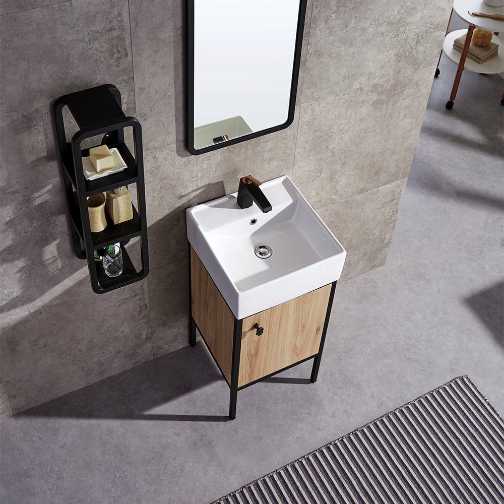 Bathroom vanity with white sink, wooden cabinet, and black shelf against a gray tiled wall.