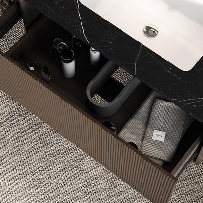 Bathroom drawer with toiletries and a towel on a marble countertop