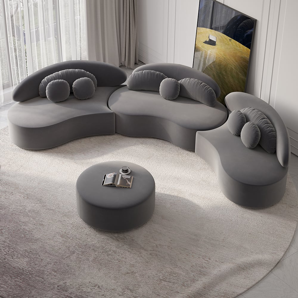 Modern deep gray sofa with a round ottoman in a minimalistic living room.