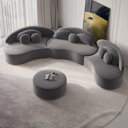 Modern deep gray sofa with a round ottoman in a minimalistic living room.