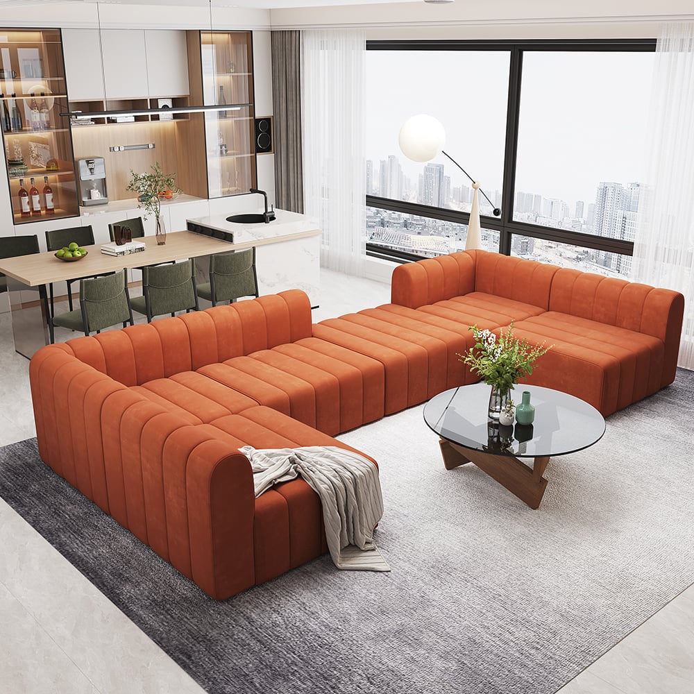 Modern living room with an orange sectional sofa, glass coffee table, and city view.